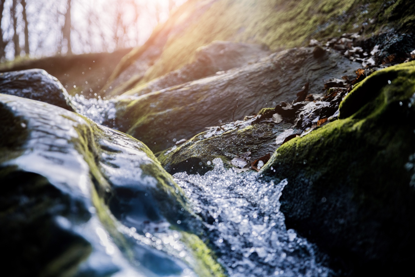 Image 9-21-25 at 6.46 PM Tight shot of river running over rocks with sunlight in the background